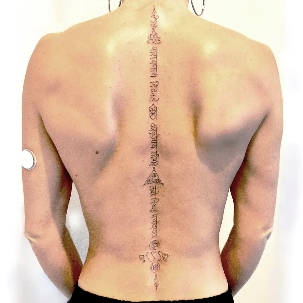 tatouage chakra colonne vertébrale femme mantra Tatouage handpoke spirituel sur la colonne vertébrale d’une femme avec symboles des chakras