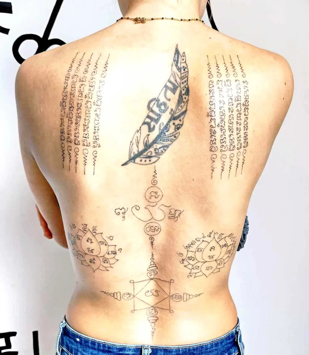 Tatouage thaïlandais Sak Yant dos complet chez une femme, lotus jumeaux et Hah Taew, écriture khom, handpoke à Bayonne
