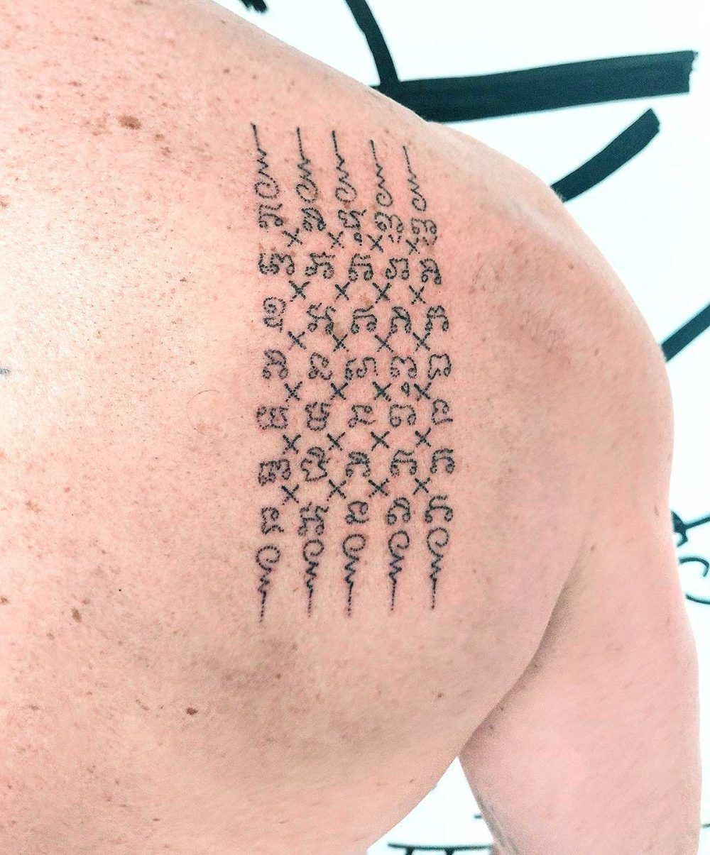 Tatouage thaïlandais Sak Yant Chat Petch sur l'épaule, écriture khom sacrée, réalisé au handpoke
