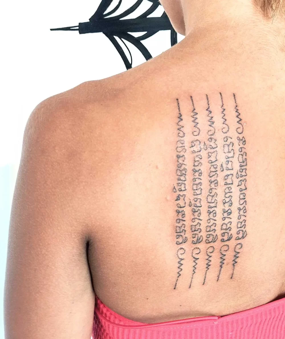 Tatouage thaïlandais Sak Yant Hah Taew cinq lignes sur l'épaule, écriture khom sacrée, réalisé au handpoke
