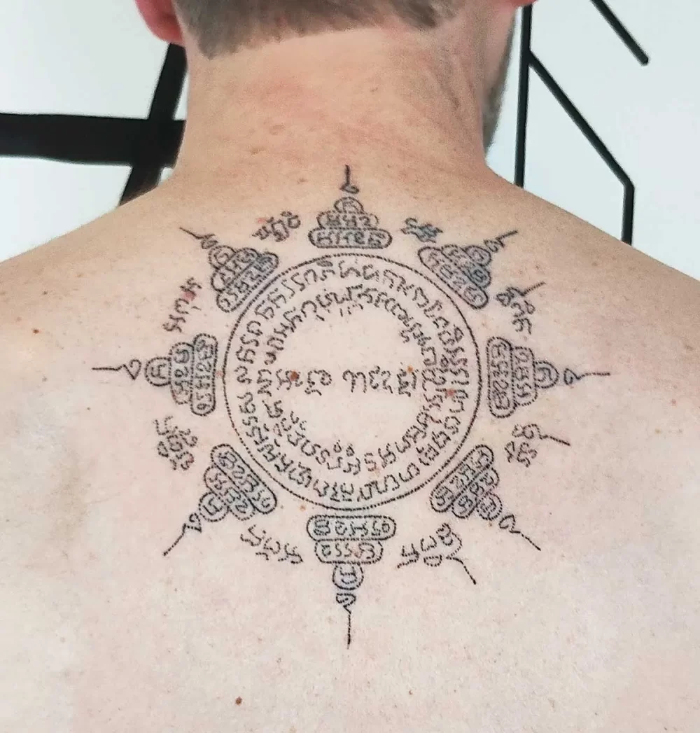 Tatouage thaïlandais Sak Yant Paed Tidt, motif des huit directions, écriture khom sacrée, réalisé au handpoke
